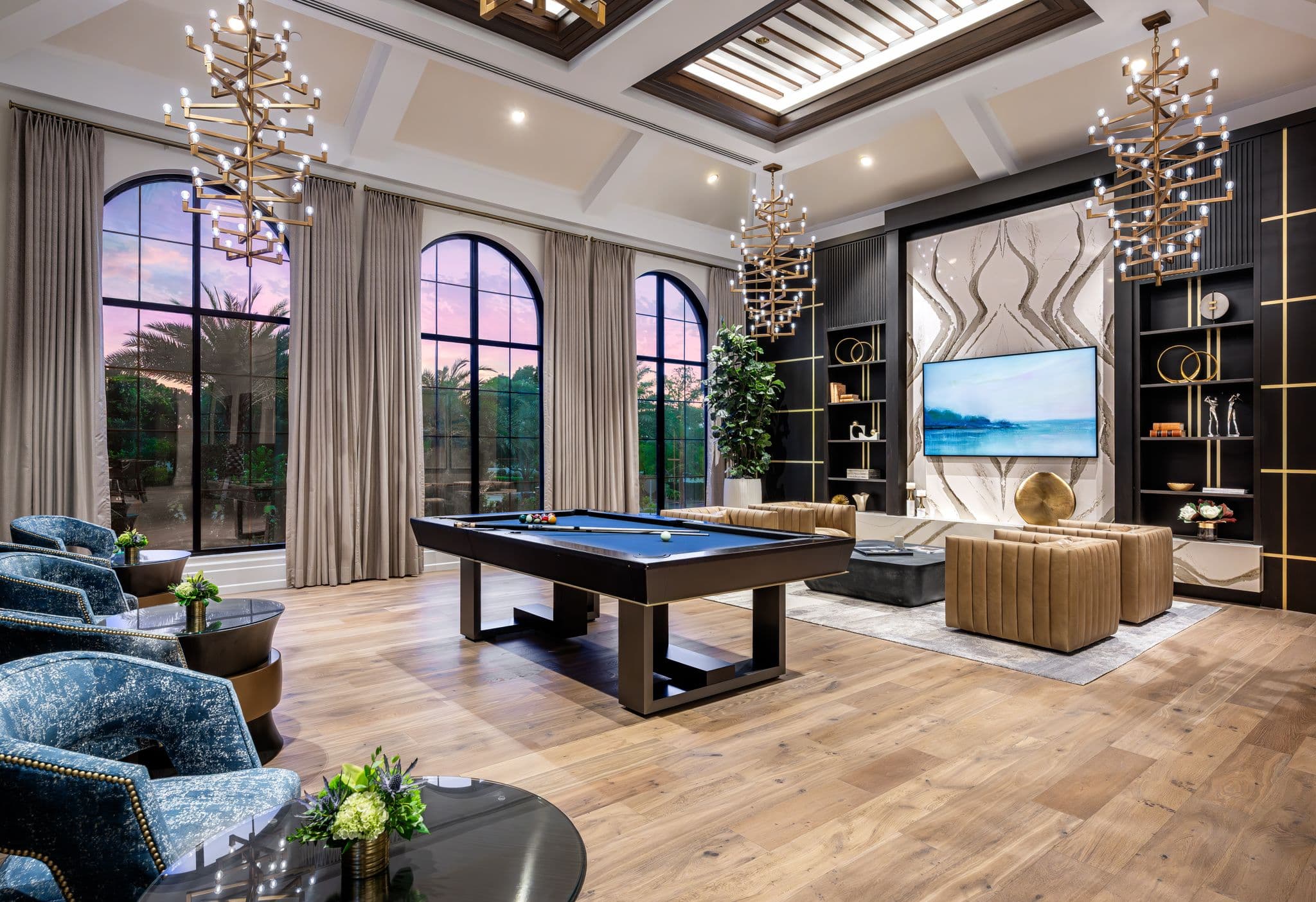 The club room, with a billiards table and lounge chairs under tall arched windows