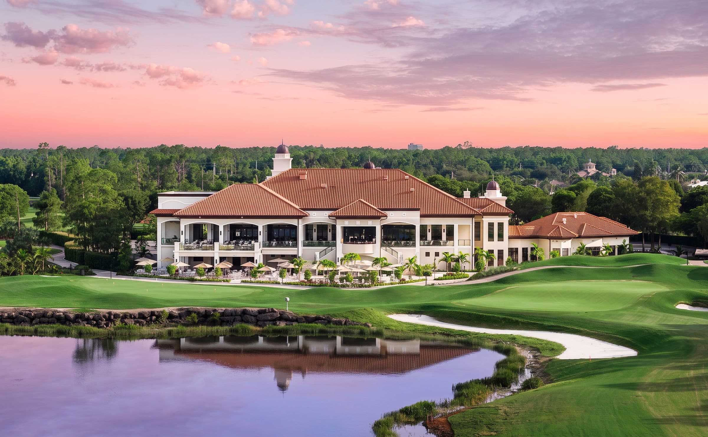 The renovated clubhouse at The Club at Olde Cypress at sunset, across a lake and green