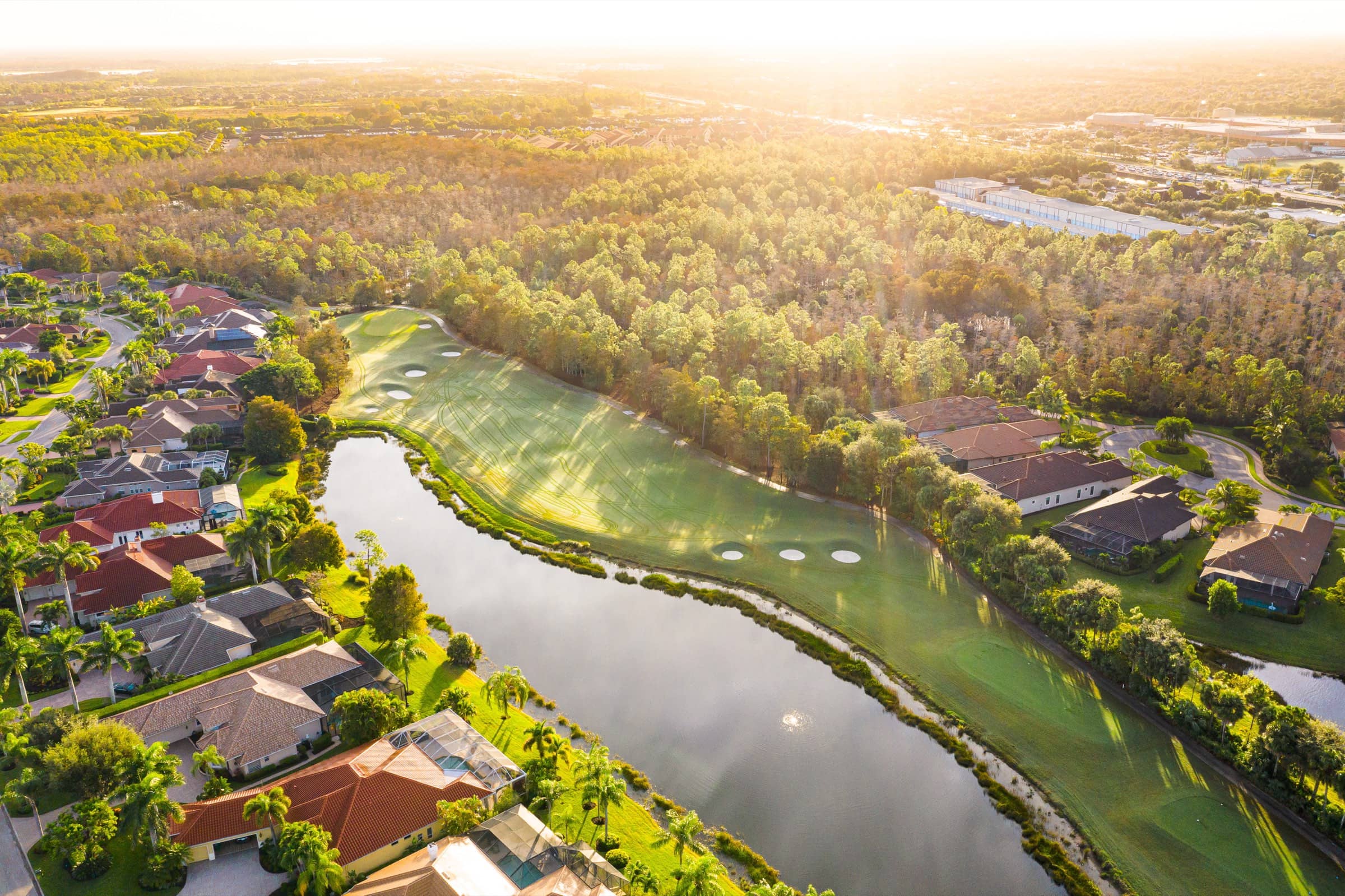 Homes along a lake and fairway at Olde Cypress at sunrise, seen from the air